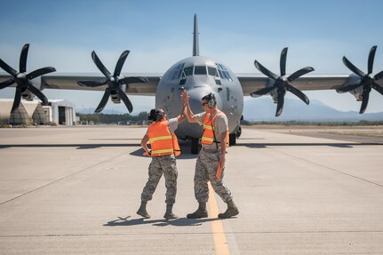 Air Force Staff Sgt. Alisha Garrette and crew chief Staff Sgt. Sean Sullivan give each other a high-five after Garrette successfully marshaled a C-130 Hercules aircraft while participating in the 612th Air Base Squadron's "Crew Chief for a Day" program at Soto Cano Air Base, March 2. The program aims to get other servicemembers from JTF-Bravo to come out to the airfield and experience a day in the life of a U.S. Air Force crew chief.