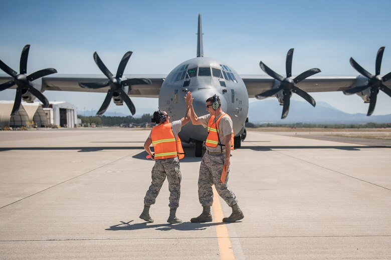 Air Force Staff Sgt. Alisha Garrette and crew chief Staff Sgt. Sean Sullivan give each other a high-five after Garrette successfully marshaled a C-130 Hercules aircraft while participating in the 612th Air Base Squadron's "Crew Chief for a Day" program at Soto Cano Air Base, March 2. The program aims to get other servicemembers from JTF-Bravo to come out to the airfield and experience a day in the life of a U.S. Air Force crew chief.