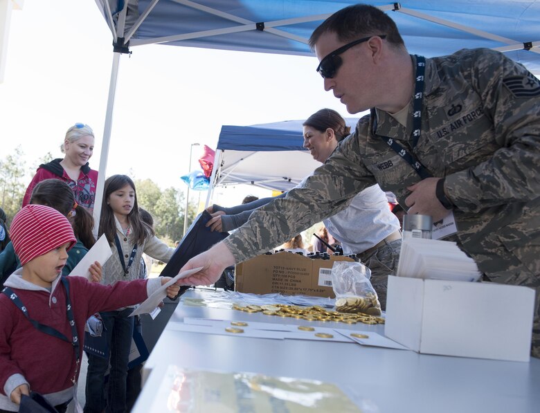 Tech. Sgt. Mark Webb, 919th Special Operations Wing, hands out some “spending money” from finance to a new deployer before their mission during the Operation Hero event at Duke Field, Fla., March 4.  The wing held a mock deployment for the Reserve children to include a deployment line, simulated flight and a “down range” location with games and displays.  (U.S. Air Force photo/Samuel King Jr.)