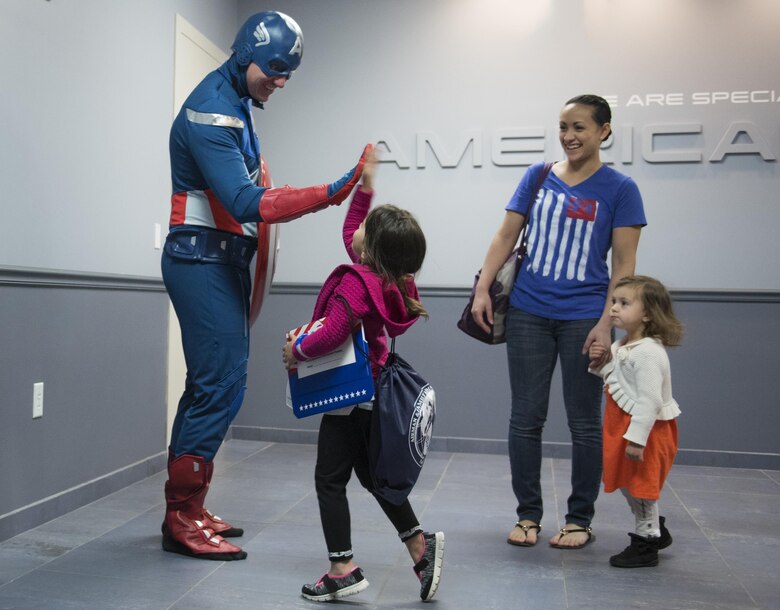 A new 919th Special Operations Wing deployer high-fives Captain America before moving out during the Operation Hero event at Duke Field, Fla., March 4.  The wing held a mock deployment for the Reserve children to include a deployment line, simulated flight and a “down range” location with games and displays.  (U.S. Air Force photo/Samuel King Jr.)