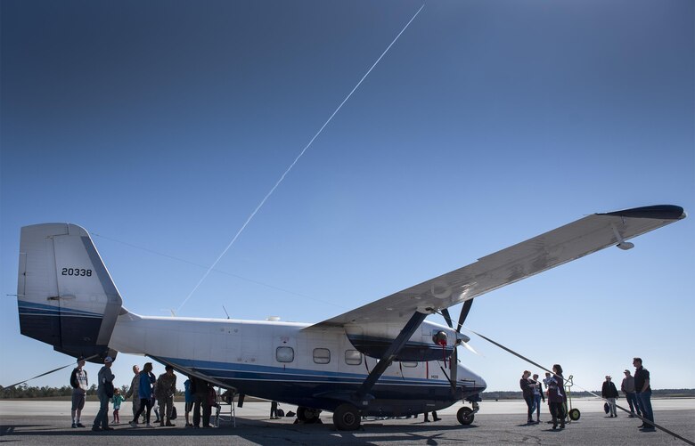 A jet streaks overhead as families check out a C-145A Skytruck display during the Operation Hero event at Duke Field, Fla., March 4.  The wing held a mock deployment for the Reserve children to include a deployment line, simulated flight and a “down range” location with games and displays.  (U.S. Air Force photo/Samuel King Jr.)