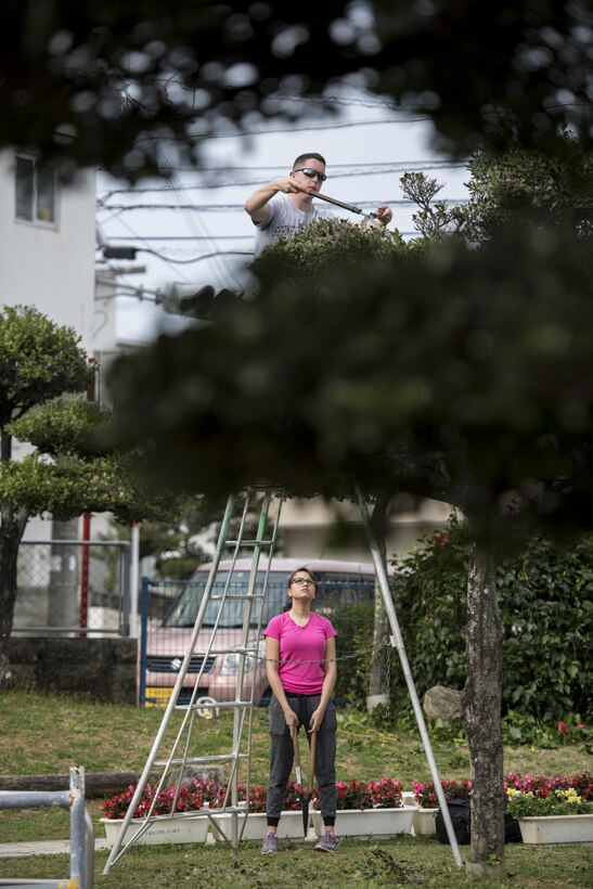 U.S. Air Force Airman Hunter Menke and Airman 1st Class Viviana Faz, 909th Aircraft Maintenance Unit apprentices, volunteer with the Kadena Ryoku Ju Kai to trim Yara Elementary School’s trees March 5, 2017, at Kadena Town, Japan. The Kadena Ryoku Ju Kai is an Okinawan government volunteer group that landscapes around Kadena Town. (U.S. Air Force photo by Senior Airman Omari Bernard/Released)