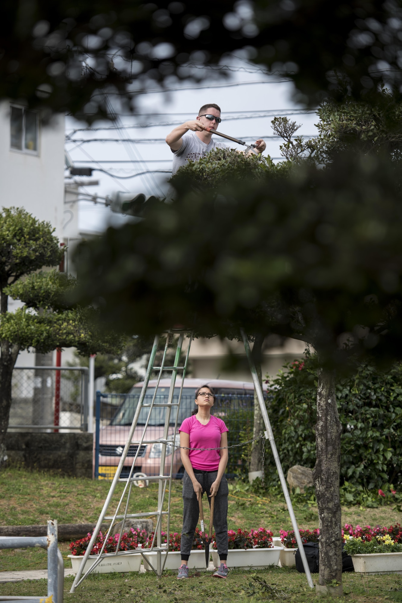 U.S. Air Force Airman Hunter Menke and Airman 1st Class Viviana Faz, 909th Aircraft Maintenance Unit apprentices, volunteer with the Kadena Ryoku Ju Kai to trim Yara Elementary School’s trees March 5, 2017, at Kadena Town, Japan. The Kadena Ryoku Ju Kai is an Okinawan government volunteer group that landscapes around Kadena Town. (U.S. Air Force photo by Senior Airman Omari Bernard/Released)