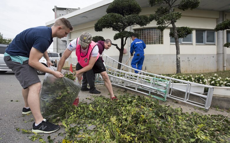 Airmen from the 909th Aircraft Maintenance Unit dispose of leaves during a volunteer event at Yara Elementary School March 5, 2017, at Kadena Town, Japan. Airmen from the 909th AMU volunteer in Kadena Town to better their selves and build community relations with local Okinawans. (U.S. Air Force photo by Senior Airman Omari Bernard/Released)