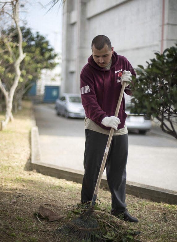 U.S. Air Force Airman Ryan Crean, 909th Aircraft Maintenance Unit aerospace propulsion apprentice, rakes leaves during a volunteer event at Yara Elementary School March 5, 2017, at Kadena Town, Japan. Airmen from the 909th AMU volunteer often in Kadena Town to be a part of the local community. (U.S. Air Force photo by Senior Airman Omari Bernard/Released)