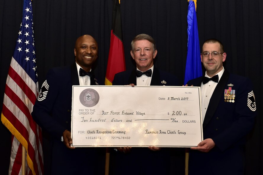 Retired Chief Master Sgt. of the Air Force Rodney J. McKinley receives a check donated in his name to the Air Force Enlisted Village from Chief Master Sgts. Robinson Joseph, left, and Edward Keenan, during the Chief Recognition Ceremony on Ramstein Air Base, Germany, March 3, 2017. McKinley, the key note speaker, discussed the responsibilities of effective leadership during his speech. (U.S. Air Force photo by Senior Airman Jonathan Bass)