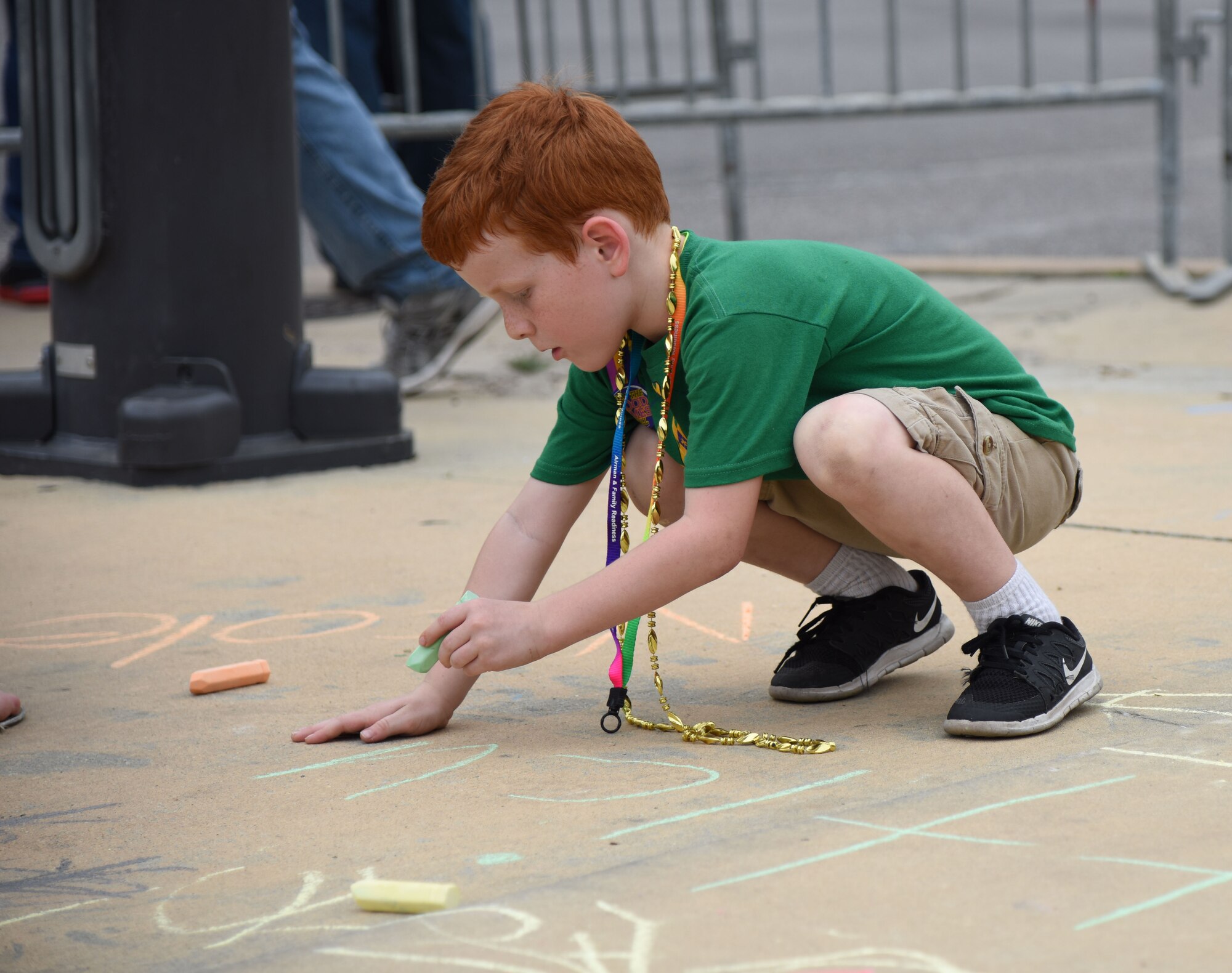 Atticus Fraites, son of Staff Sgt. Douglas Fraites, 85th Engineering Installation Squadron radio frequency transmissions team chief, draws on the side walk during the Gulf Coast Carnival Association Mardi Gras parade Feb. 28, 2017, in Biloxi, Miss. The 81st Force Support Squadron’s Airman and Family Readiness Center staff invited families of deployed members to the event and provided food and entertainment to them prior to the start of the parade. (U.S. Air Force photo by Kemberly Groue)