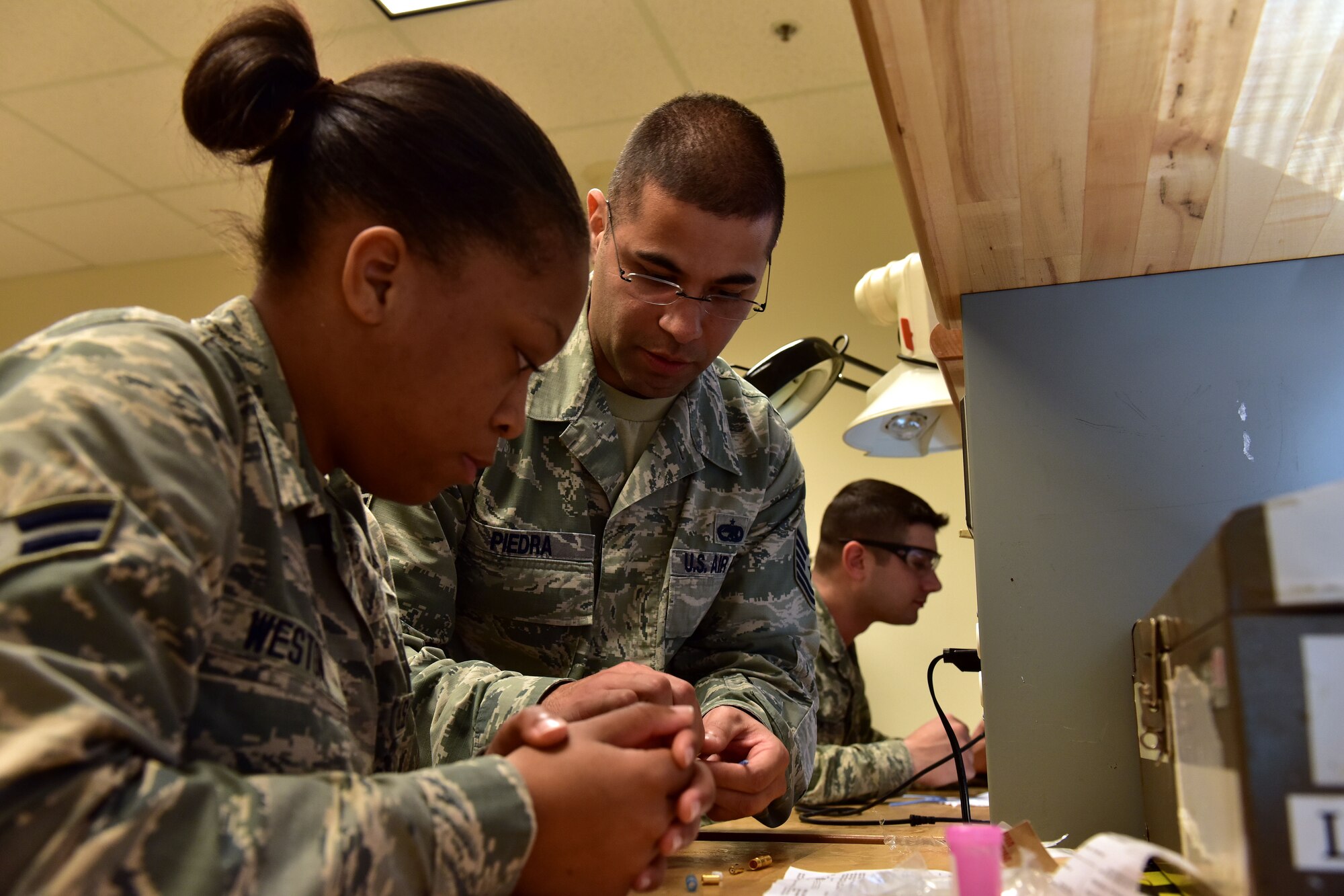 U.S. Air Force Tech. Sgt. Jose Piedra, center, 373rd Training Squadron Detachment 4 production supervisor and instructor, demonstrates splicing and building a 1553B databus cable to Airman 1st Class Shania Westin, left, 373rd TRS student, for the C-130J Feb. 23, 2017 at the Center of Excellence on Little Rock Air Force Base, Ark.  The Airman must understand how the cable functions as it transfers information throughout the aircraft and be able to build new ones effectively. (U.S. Air Force photo by Staff Sgt. Jeremy McGuffin)