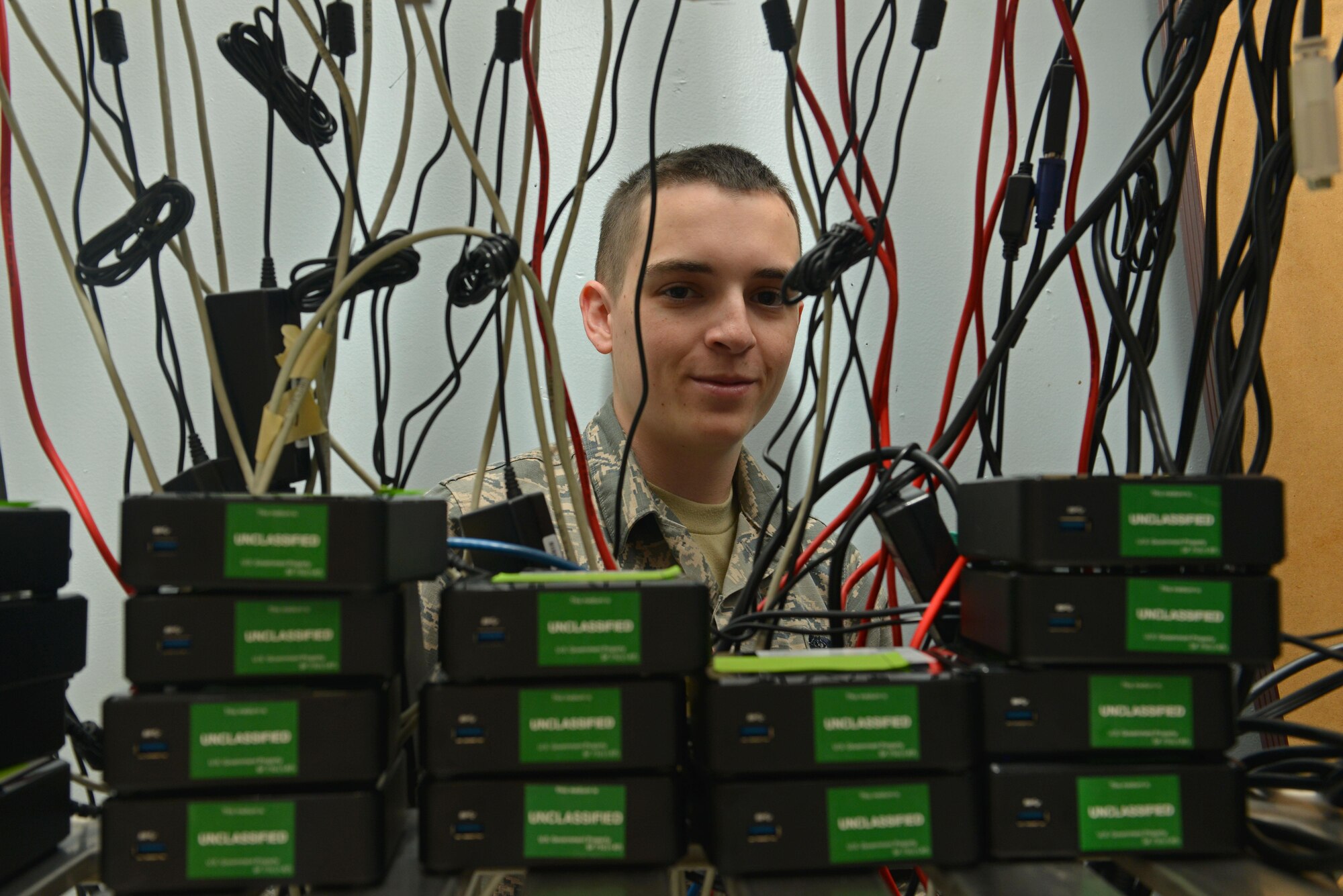 U.S. Air Force Airman 1st Class Hunter Pendry, 20th Communications Squadron client systems technician, smiles from between wires at Shaw Air Force Base, S.C., March 2, 2017. The 20th CS client service center repairs and protects all 20th Fighter Wing communication devices. Their mission statement is to provide combat-ready Airmen to ensure mission communications on time, every time. (U.S. Air Force photo by Airman 1st Class Destinee Sweeney)
