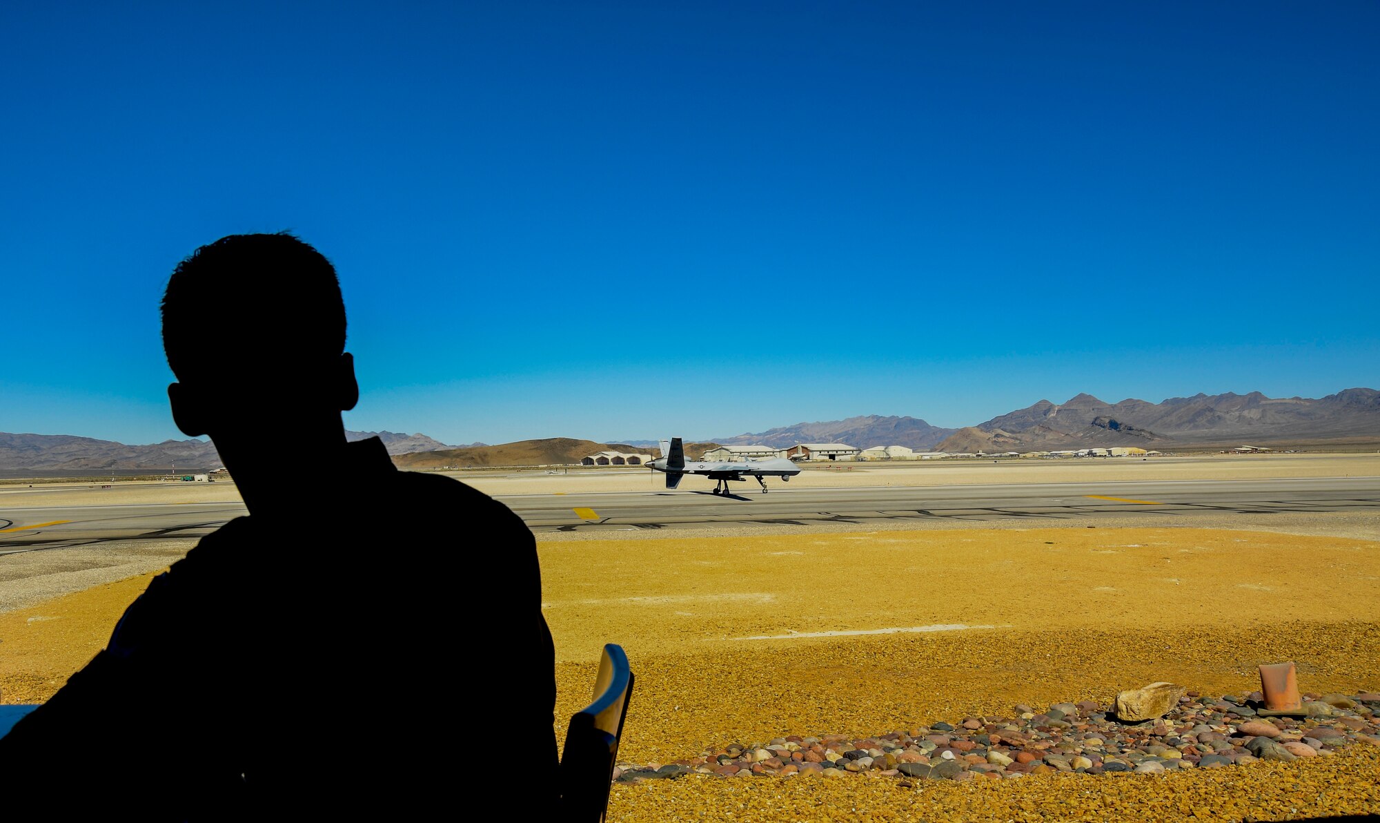 An Airman assigned to the 11th Attack Squadron watches an MQ-9 Reaper land on the runway March 3, 2017, at Creech Air Force Base, Nev. The 11th ATKS became the first remotely piloted aircraft squadron in the Air Force in 1995 and continues to conduct MQ-1 Predator and MQ-9 Reaper aircrew launch and recovery training today. (U.S. Air Force photo illustration/Airman 1st Class James Thompson)
