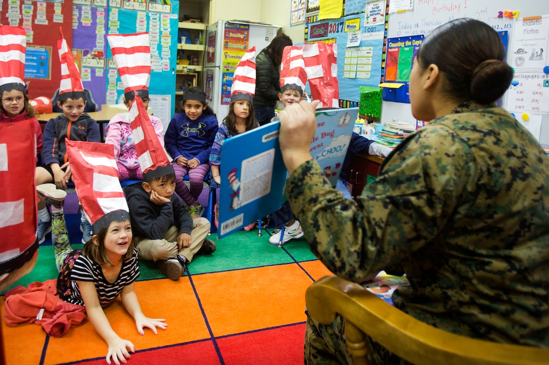 Marine Corps Lance Cpl. Saddie Martinez shows pictures from the book she's reading to students during Read Across Department of Defense Education Activity Day at Camp Foster, Okinawa, Japan, March 2, 2017. She also encouraged the students to say “Ka-choo” with her each time she read it. Martinez is a supply warehouse clerk assigned to Marine Wing Headquarters Squadran 1, 1st Marine Aircraft Wing, 3rd Marine Expeditionary Force. Marine Corps photo by Pfc. Danielle Prentice