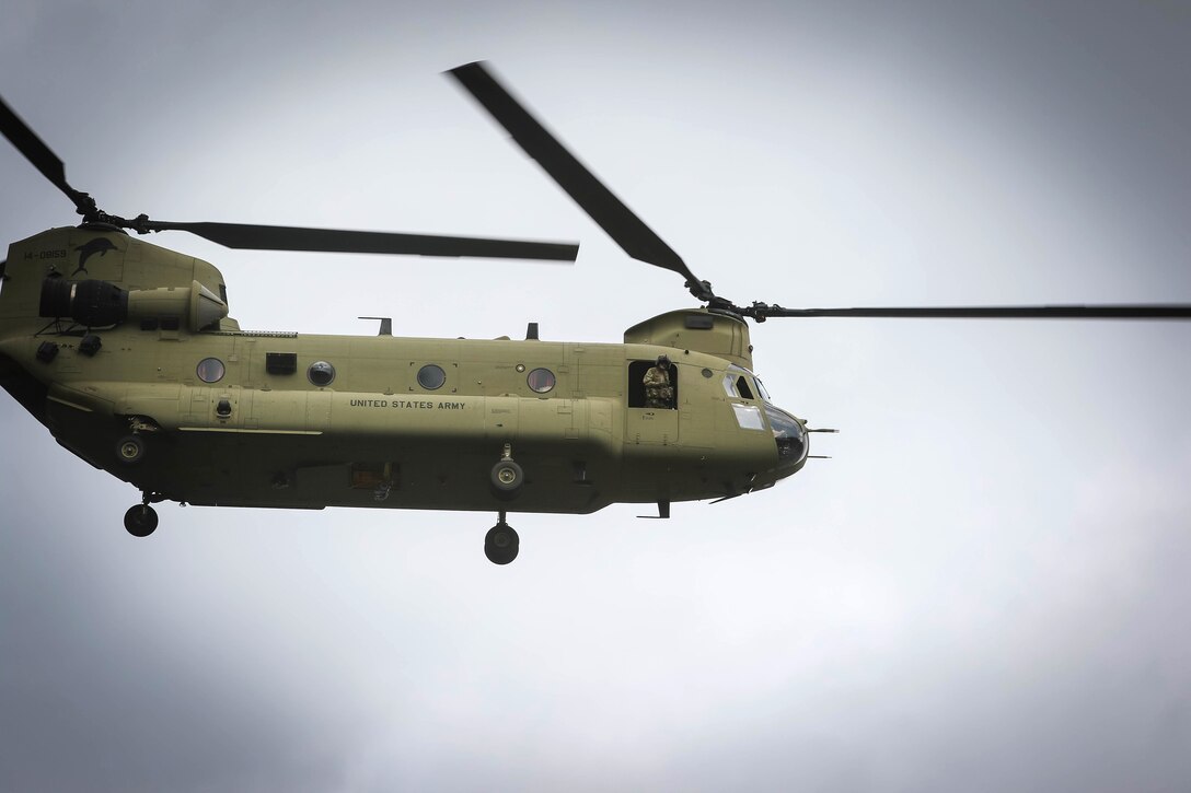 An Army crew chief leans out an open window, observing for clearance as pilots land a CH-47 Chinook helicopter at Marine Corps Outlying Field Atlantic, N.C., March 2, 2017. Army photo by Sgt. Steven Galimore