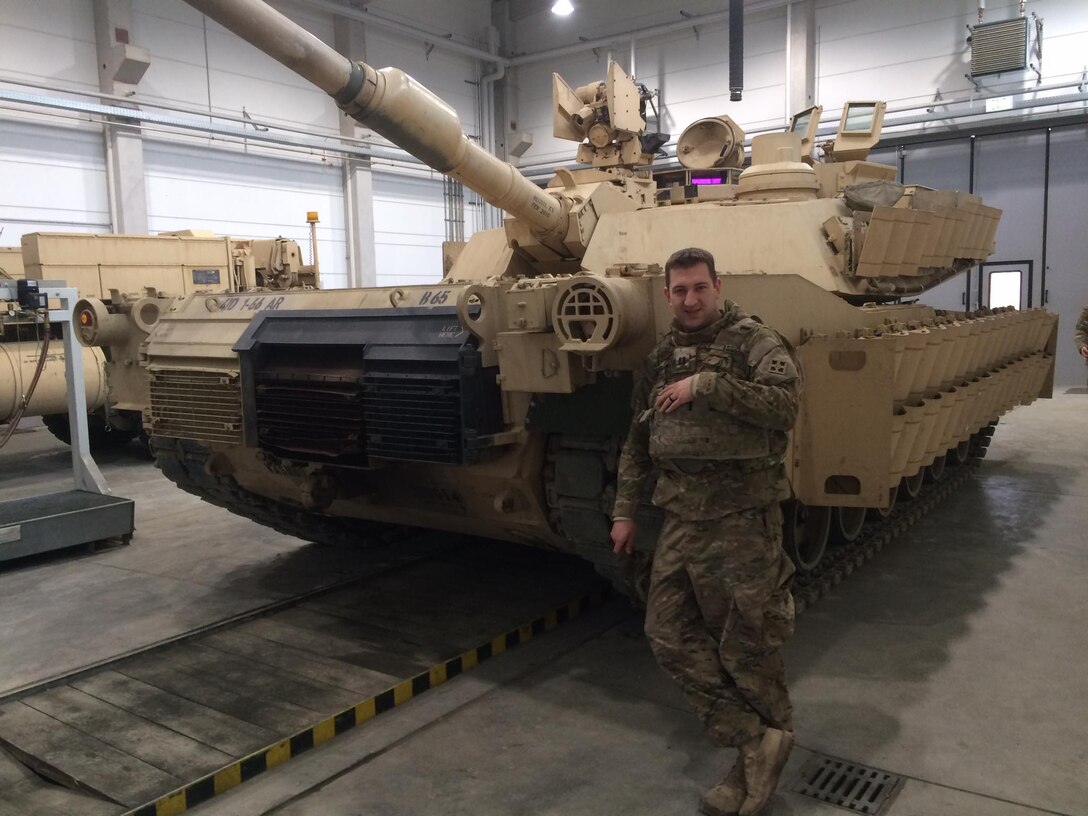 Army Capt. James England, commander, Bravo Company, 1st Battalion, 66th Armor Regiment, stands in front of an M1A2 Abrams main battle tank with newly installed reactive armor tiles  at the 7th Army Training Command's Grafenwoehr Training Area, Germany, Feb. 28, 2017. Army photo by Capt. (Chaplain) Malcolm Rios