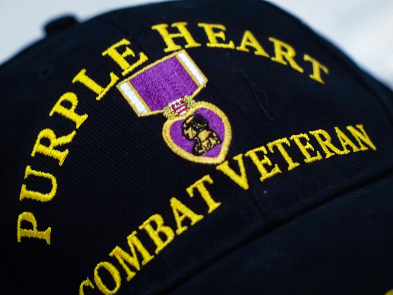 A Purple Heart Combat Veteran baseball cap rests at a table during the 38th Annual Veterans’ Luncheon at Barksdale Air Force Base, La., March, 3, 2017. The Purple Heart is awarded to members of the armed forces of the U.S. who are wounded by an instrument of war in the hands of the enemy and posthumously to the next of kin in the name of those who are killed in action or die of wounds received in action. It is specifically a combat decoration. (U.S. Air Force photo/Senior Airman Mozer O. Da Cunha)