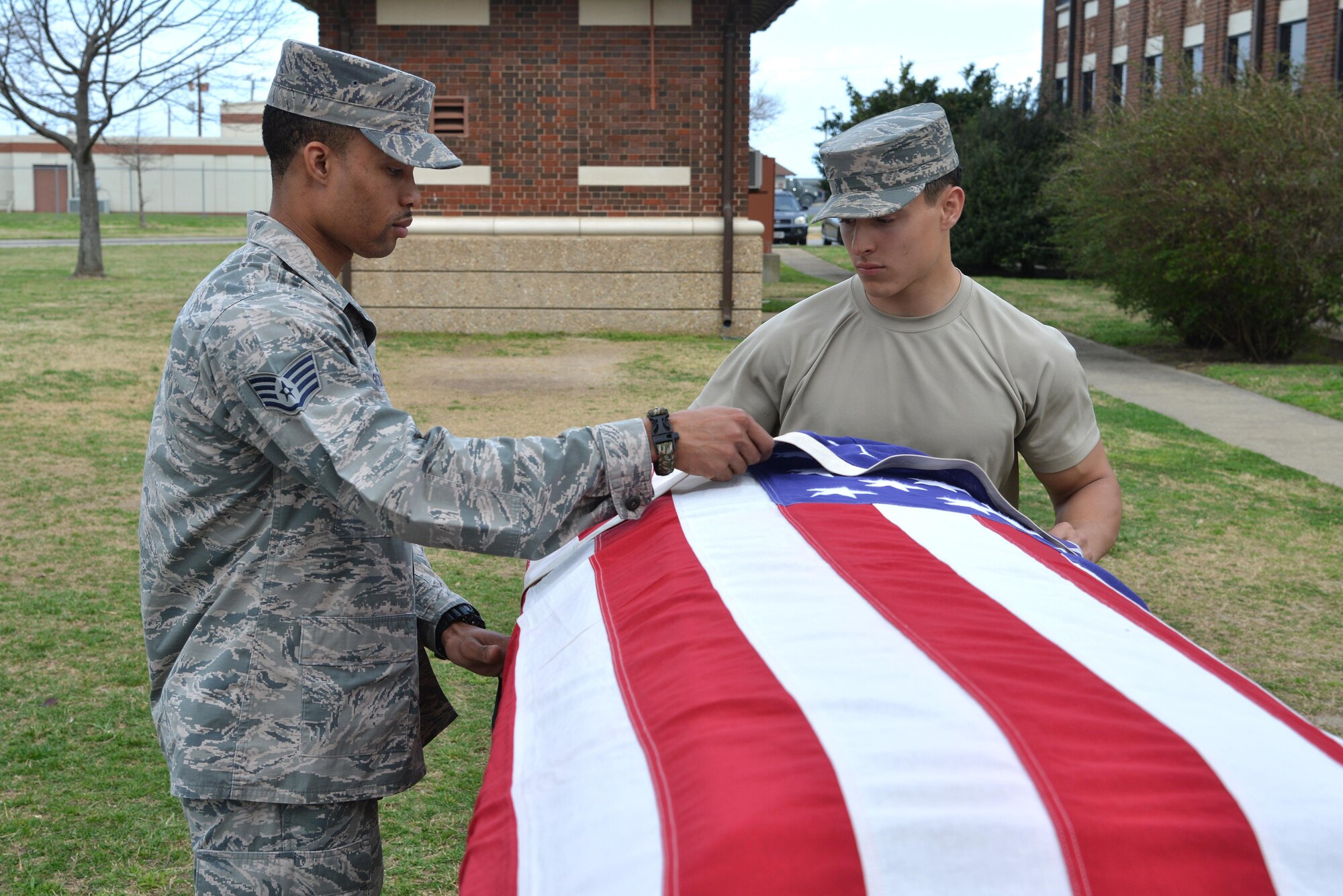 U.S. Air Force Staff Sgt. Quinton Gittens, 633rd Force Support Squadron readiness NCO in charge, assists Airman 1st Class Noah Lalonde, 633rd FSS honor guard head trainer, during honor guard training at Joint Base Langley-Eustis, Va., March 1, 2017. Gittens has dedicated seven years to the Langley Honor Guard.(U.S. Air Force photo by Airman 1st Class Tristan Biese)