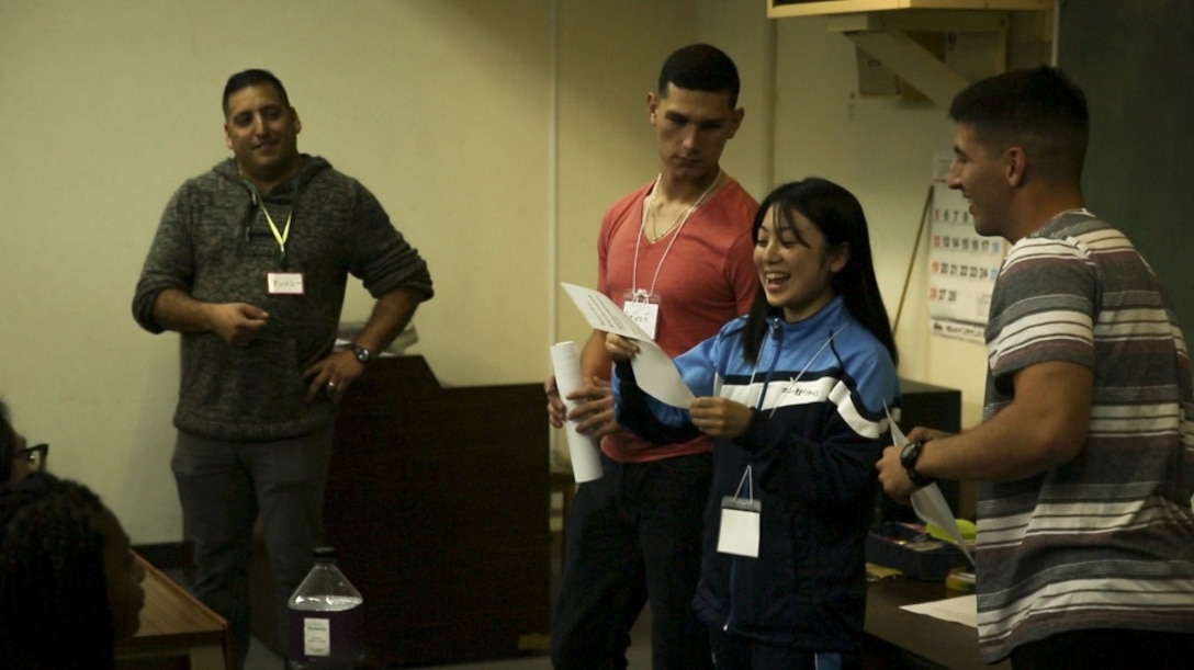 Private First Class Devon J. Ridenour (left) and Lance Cpl. Giovanni L. Ramires (right), both intelligence specialists with 3rd Intelligence Battalion, III Marine Expeditionary Force Headquarters Group, and an Okinawan resident present a class project during the Kin-Hansen Friendship English Class at the Kin Town Central Community Center, in Kin Town, Okinawa, Japan, Feb. 28, 2017. The Kin-Hansen English Class is a weekly English conversational class hosted to strengthen the bond between Okinawans and service members. Ridenour is a native of Phoenix; Ramires is from Johnstown, Pennsylvania. (U.S. Marine Corps photo by Lance Cpl. Andy Martinez) 