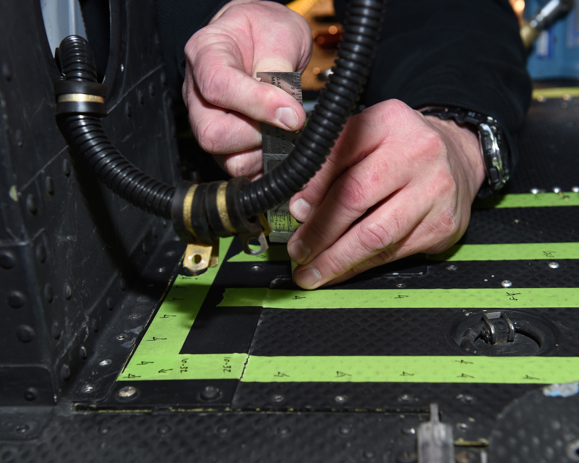 An aircraft mechanic measures the gap in between holes where rivets will be secured as new floor paneling is installed on a UH-1N Huey helicopter during a scheduled phase maintenance inspection on the aircraft March 6, 2017, at Malmstrom Air Force Base, Mont.  The phase inspection period usually lasts 4 to 6 weeks and routinely occurs after 400 flight hours.  (U.S. Air Force photo/Jason Heavner)