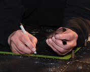An aircraft mechanic marks where rivets are going to go as floor panels are installed on a UH-1N Huey helicopter during a scheduled phase maintenance inspection on the aircraft March 6, 2017, at Malmstrom Air Force Base, Mont.  The phase inspection period usually lasts 4 to 4 weeks and routinely occurs after 400 flight hours.  (U.S. Air Force photo/Jason Heavner)