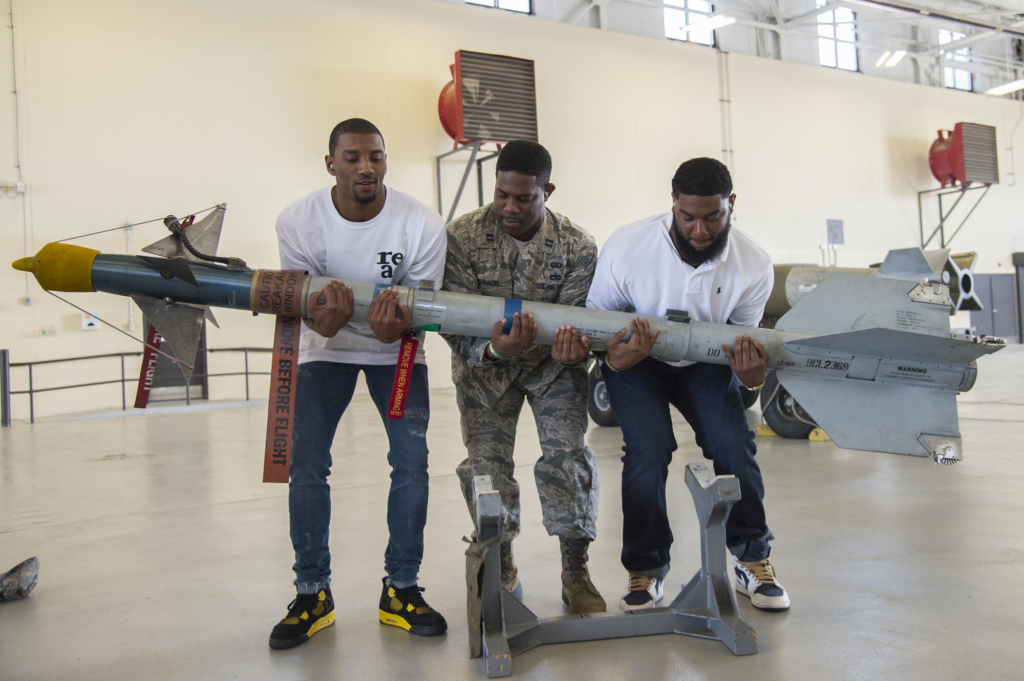 Malcolm Mitchell, left, New England Patriots’ wide receiver and Super Bowl LI Champion, Capt. Eric Johnson, 23d Civil Engineer Squadron commander, and James Rome, former Pittsburgh Steeler tight end, lift an AIM 9 Sidewinder II missile during Mitchell’s visit March 7, 2017, at Moody Air Force Base, Ga. Mitchell, a Valdosta native, got a glimpse of a typical day in the life of Moody Airmen. Mitchell also spent time with Airmen and signed autographs for local Patriots’ fans during his visit. (U.S. Air Force photo by Senior Airman Ceaira Young)