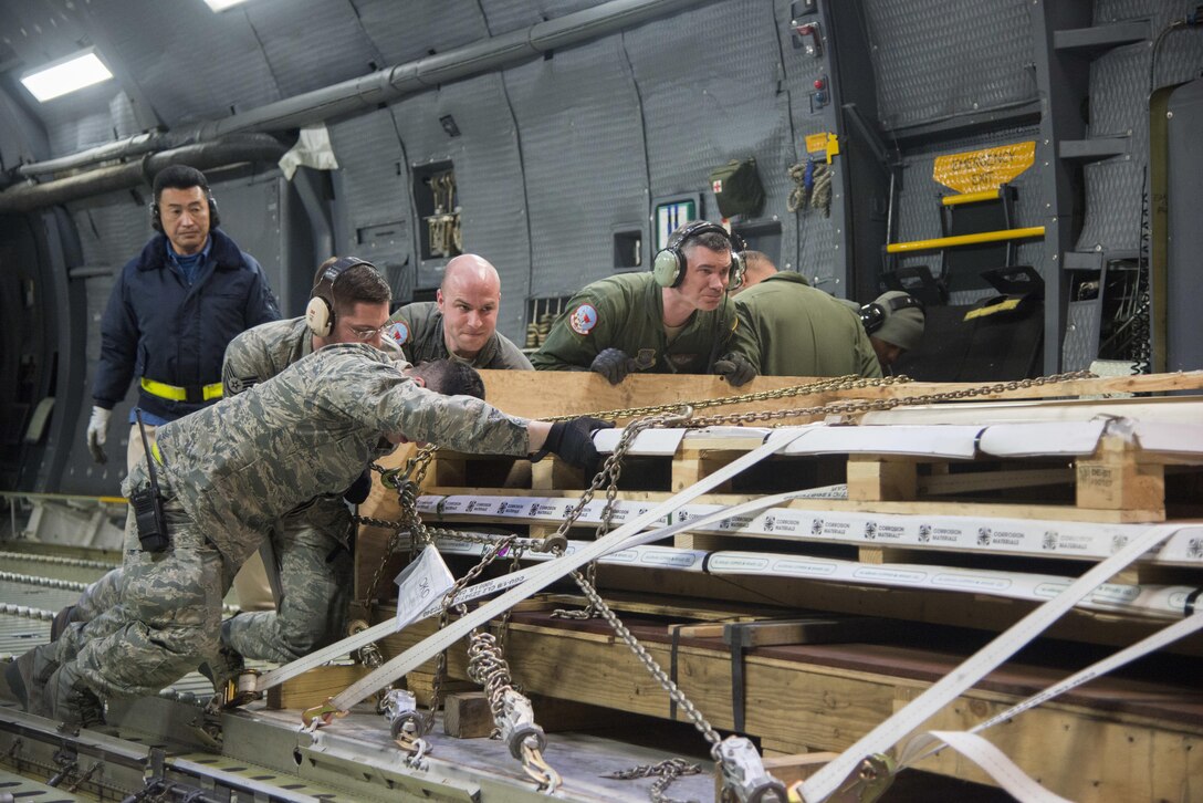 Airmen from the 22nd Airlift Squadron and the 730th Air Mobility Squadron, download cargo off of a C-5M Super Galaxy after arriving at Yokota Air Base, Japan, March 5, 2017. The team worked together to offload nearly 50,000 pounds of various cargo. (U.S. Air Force photo/Staff Sgt. Nicole Leidholm)