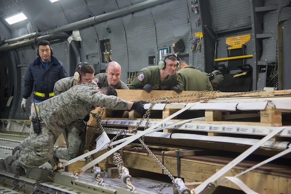Airmen from the 22nd Airlift Squadron and the 730th Air Mobility Squadron, download cargo off of a C-5M Super Galaxy after arriving at Yokota Air Base, Japan, March 5, 2017. The team worked together to offload nearly 50,000 pounds of various cargo. (U.S. Air Force photo/Staff Sgt. Nicole Leidholm)