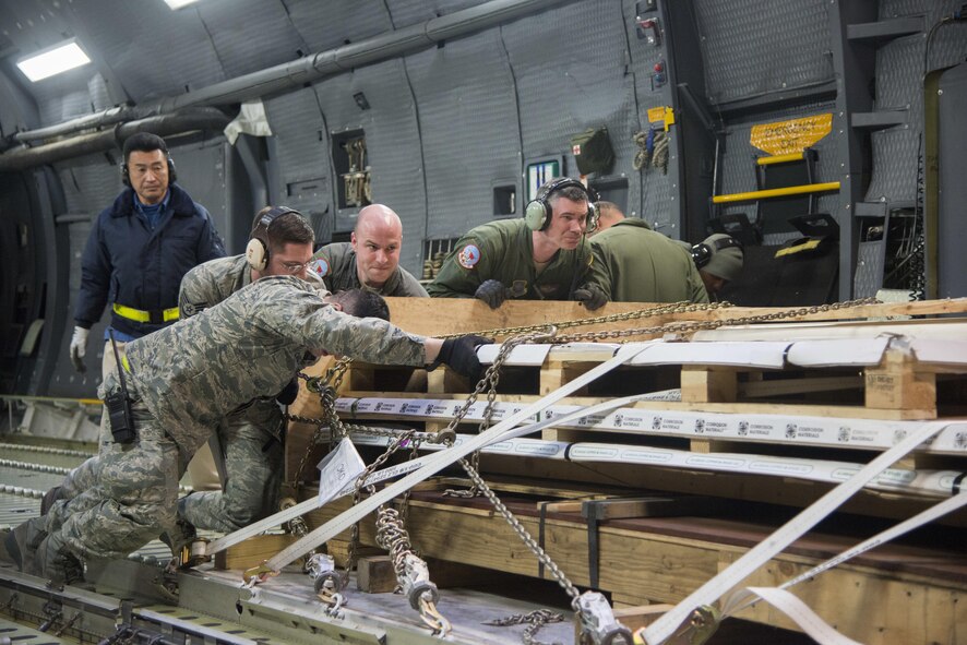 Airmen from the 22nd Airlift Squadron and the 730th Air Mobility Squadron, download cargo off of a C-5M Super Galaxy after arriving at Yokota Air Base, Japan, March 5, 2017. The team worked together to offload nearly 50,000 pounds of various cargo. (U.S. Air Force photo/Staff Sgt. Nicole Leidholm)