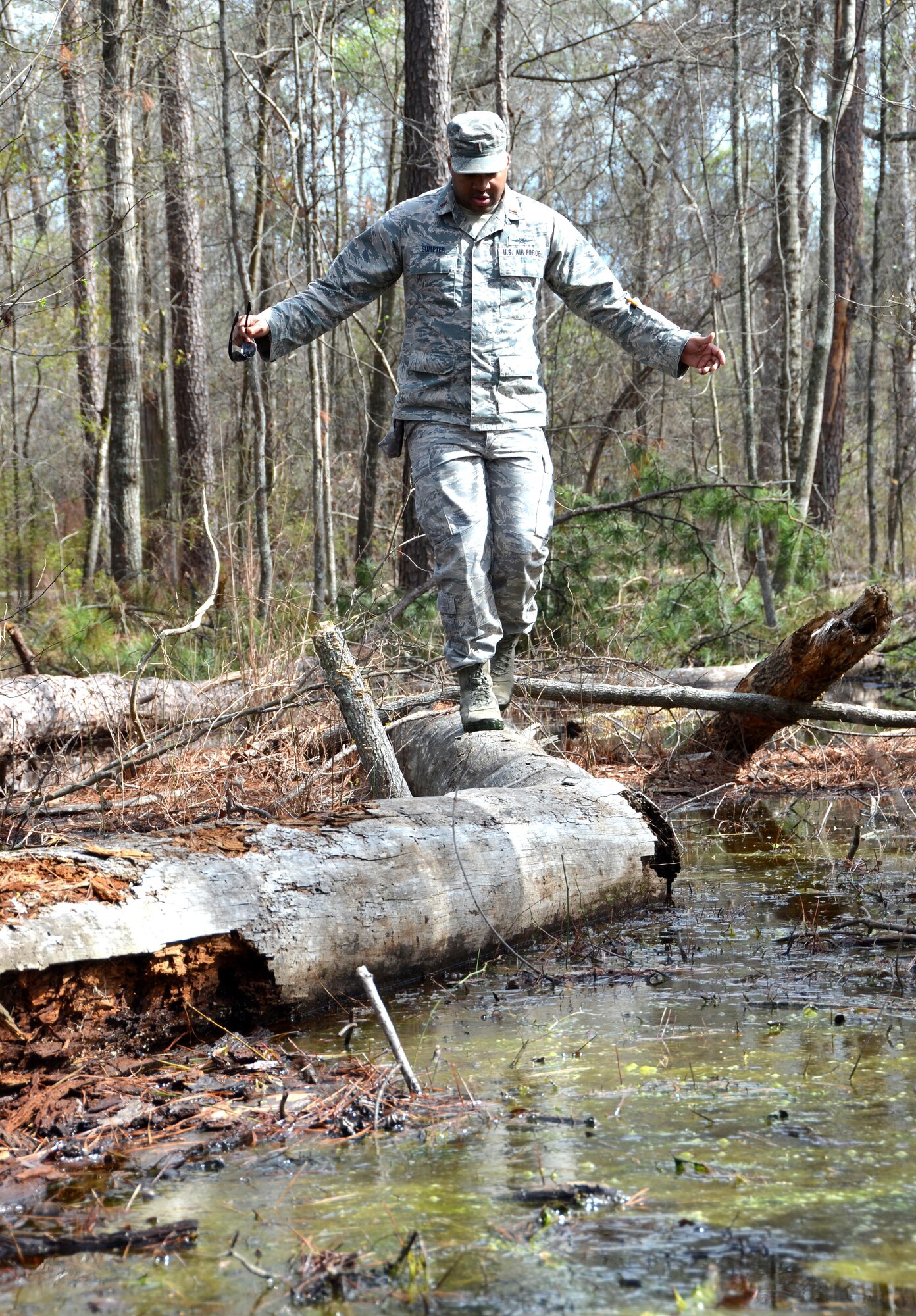 Second Lieutenant Steven Sumpter, 729th Air Control Squadron, balances himself ontop a fallen tree while navigating across a flooded area to get to the designated marker during a land navigation exercise on Robins Air Force Base, Ga., March 2, 2017. The 5th CCG provides a two-week course for a maximum of 34 students and cover a variety of topics such as land navigation, improvised explosive device detection, and much more. (U.S. Air Force photo by Tech. Sgt. Kelly Goonan/released)