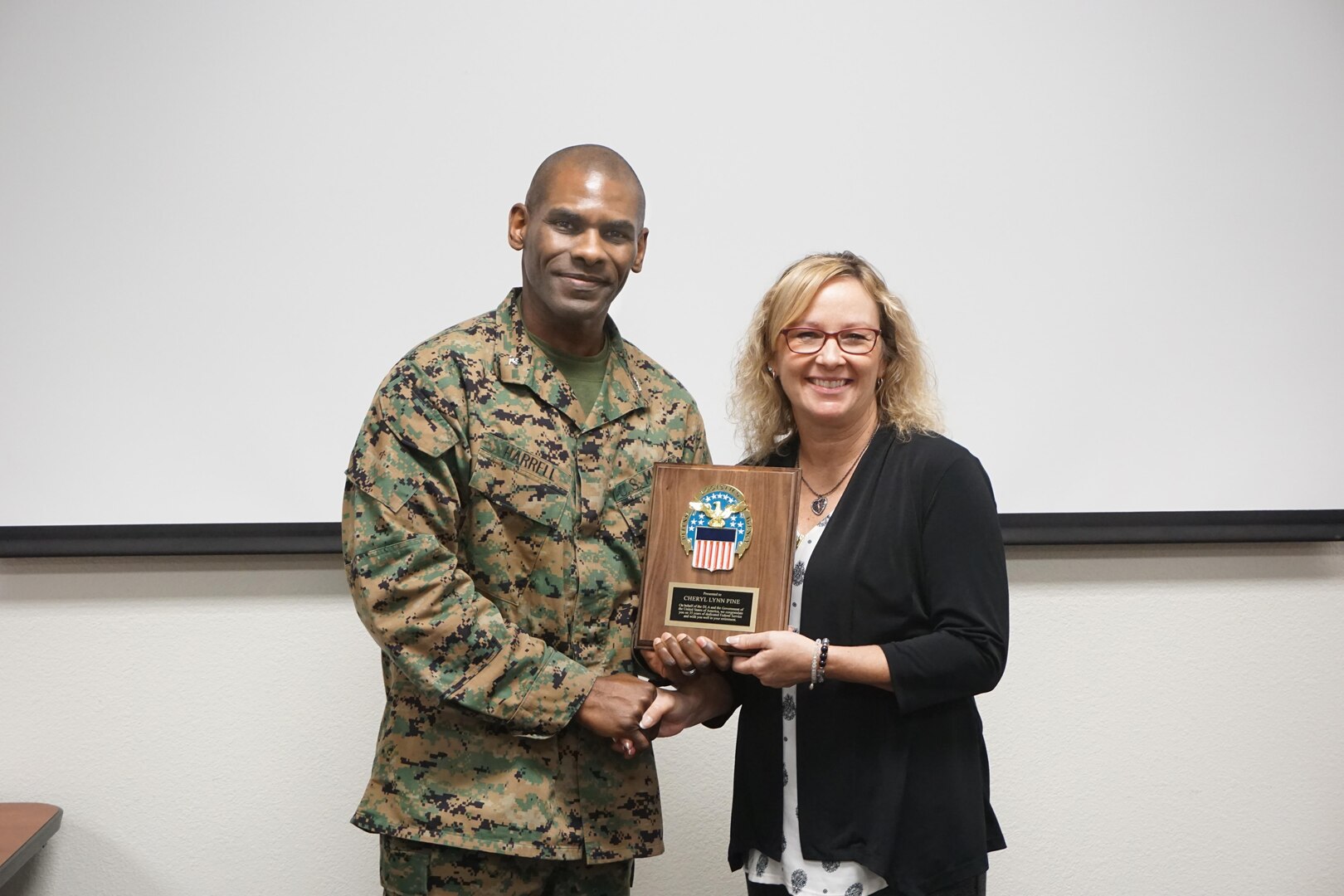 Cheryl Pine and Marine Col Dre Harrell, DLA Distribution San Joaquin, California commander, pose for a picture with the DLA retirement plaque. Pine is retiring after 35 years of dedicated federal service.