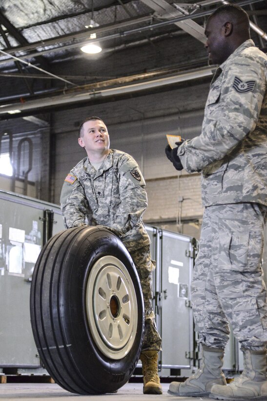 U.S. Army Spc. Eugene Lovejoy, 368th Seaport Operations Company, 11th Transportation Battalion, 7th Transportation Brigade (Expeditionary) motor pool clerk, receives guidance from U.S. Air Force Tech. Sgt. Jeremy Roberts, 733rd Logistic Readiness Squadron readiness spares package NCO in charge,  on how to properly load a tire at Joint Base Langley-Eustis, Va., March 2, 2017. The 733rd LRS worked with the 7th Transportation Brigade’s supply specialists during a week-long training to showcase the Air Force’s supply management processes. (U.S. Air Force photo by 1st Lt. Mahalia Frost)