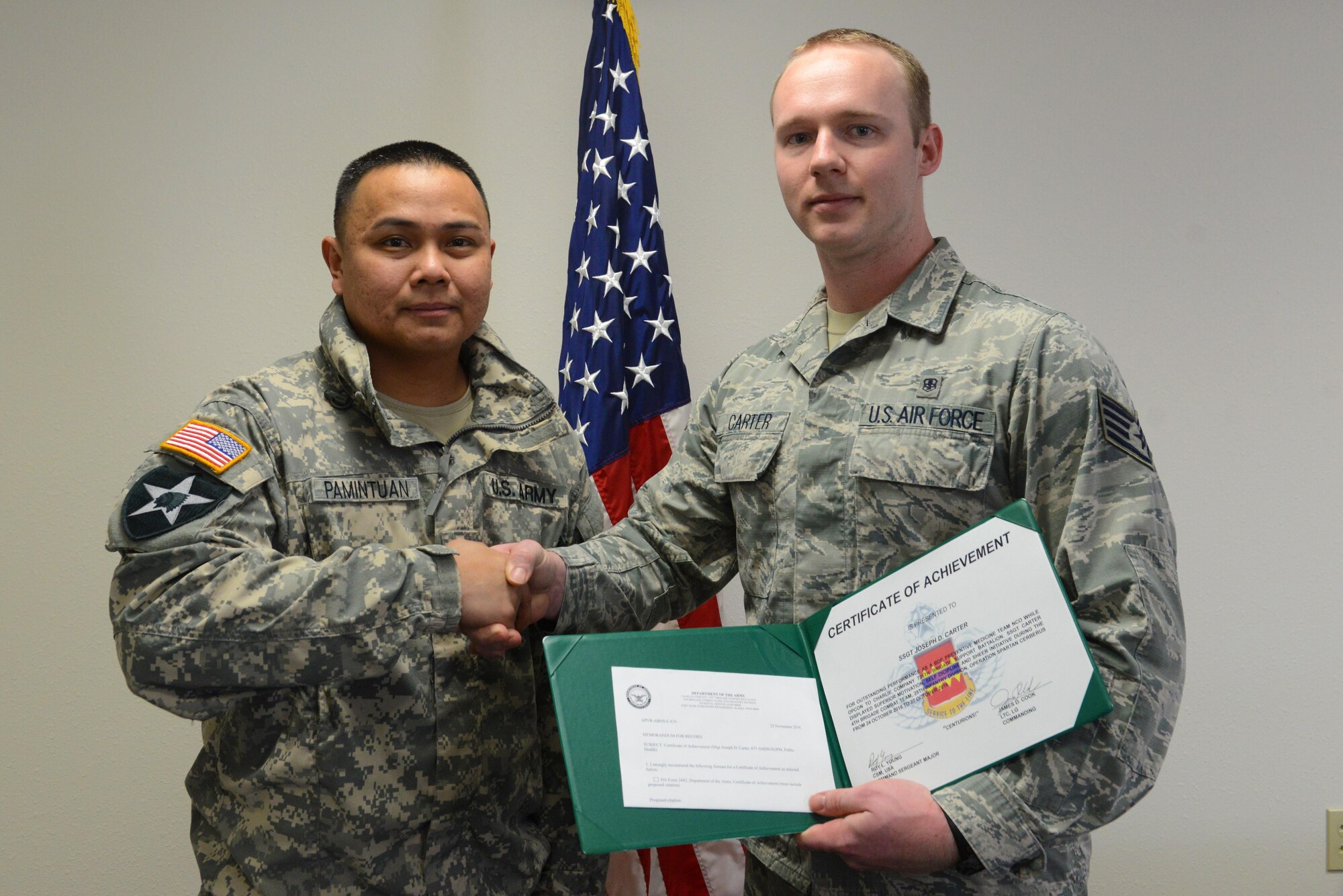 Army Capt. Bryan Pamintuan, Commander of C Company, 725th Brigade Support Battalion, awards Air Force Staff Sgt. Joseph Carter, 673d Aerospace Medical Squadron public health technician, a certificate of achievement for his role in Operation Spartan Cerberus at Joint Base Elmendorf-Richardson, Alaska, Feb. 27, 2017. He performed duties of an Army preventive medicine specialist by conducting preventive medical inspections and showing initiative by providing assistance solving several discrepancies. 