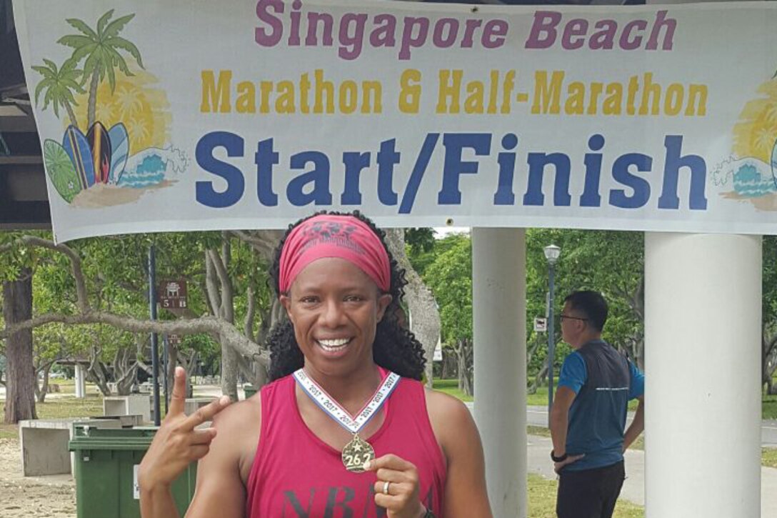 Enjoying a little bit of sunshine, retired Marine Shalisa Davis stands in front of the start/finish line in Singapore Beach, Singapore after finishing lucky number two. Photo by Shalisa Davis
