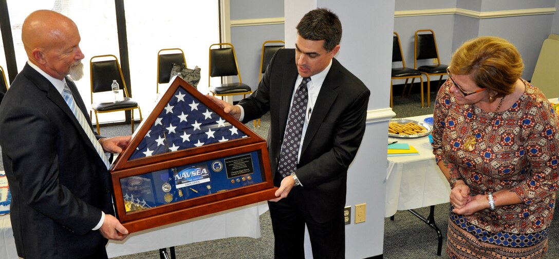 DAHLGREN, Va. (March 3, 2017) - NSWC Dahlgren Division Deputy Technical Director Dale Sisson, center, presents Christine Mason with a shadow box at her retirement ceremony, which serves to award her the Navy Meritorious Civilian Service award for her many accomplishments and her continued dedication and service to the US Navy. Holding the gift item with Sisson is Christine's husband Vic.  The shadow box displays the flag flown over NSWCDD headquarters on Jan. 25, 2017 in honor and grateful appreciation of Christine's 37 years of dedicated service to the U.S. Navy and the nation. Christine served as deputy Enterprise Resource Planning (ERP) Site Implementation Lead (SIL) through ERP deployment and as ERP SIL through stabilization and sustainment the past 8 years.  