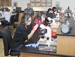 Petty Officer1st Class Elizabeth Sifuentes, a medical laboratory technician instructor at the Medical Education and Training Campus, talks to students from John Marshall High School while they look through microscopes during a tour of METC at Joint Base San Antonio-Fort Sam Houston. The tour was conducted by METC's Navy service component, Navy Medicine Training Support Center, as part of their Science, Technology, Engineering and Mathematics, or STEM, efforts.