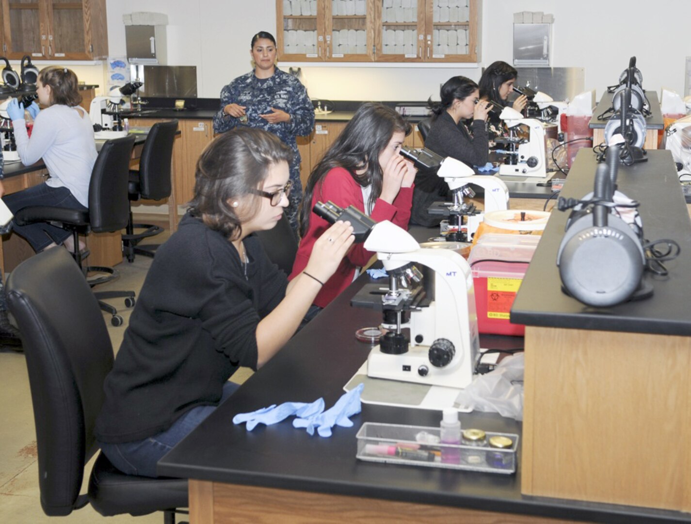 Petty Officer1st Class Elizabeth Sifuentes, a medical laboratory technician instructor at the Medical Education and Training Campus, talks to students from John Marshall High School while they look through microscopes during a tour of METC at Joint Base San Antonio-Fort Sam Houston. The tour was conducted by METC's Navy service component, Navy Medicine Training Support Center, as part of their Science, Technology, Engineering and Mathematics, or STEM, efforts.