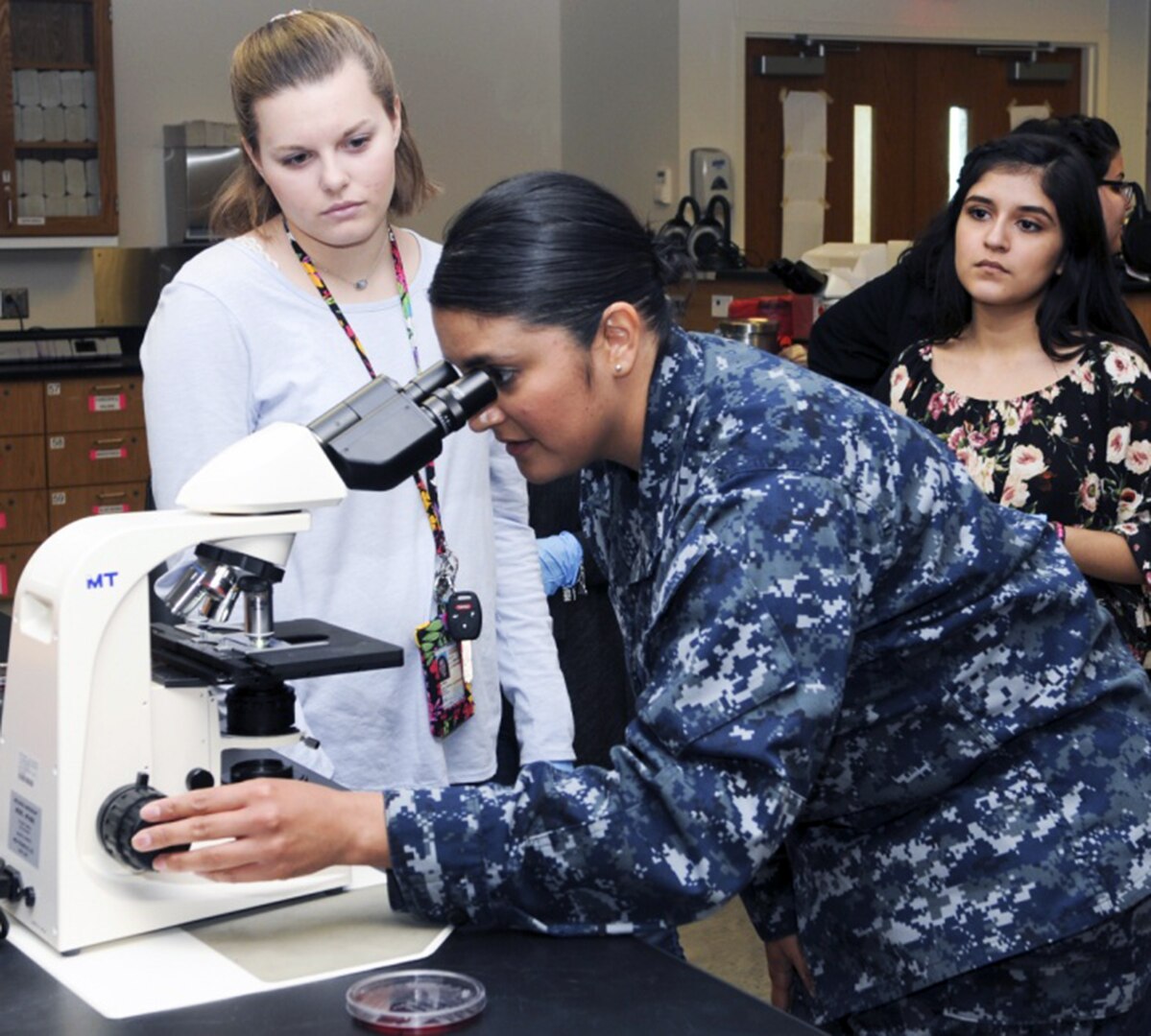 Petty Officer 1st Class Elizabeth Sifuentes, a medical laboratory technician instructor at the Medical Education and Training Campus, adjusts a microscope for students from John Marshall High School to show them different organisms medical lab technicians work with during a tour of METC at Joint Base San Antonio-Fort Sam Houston March 2. The tour was conducted by METC's Navy service component, Navy Medicine Training Support Center, as part of their Science, Technology, Engineering and Mathematics, or STEM efforts.