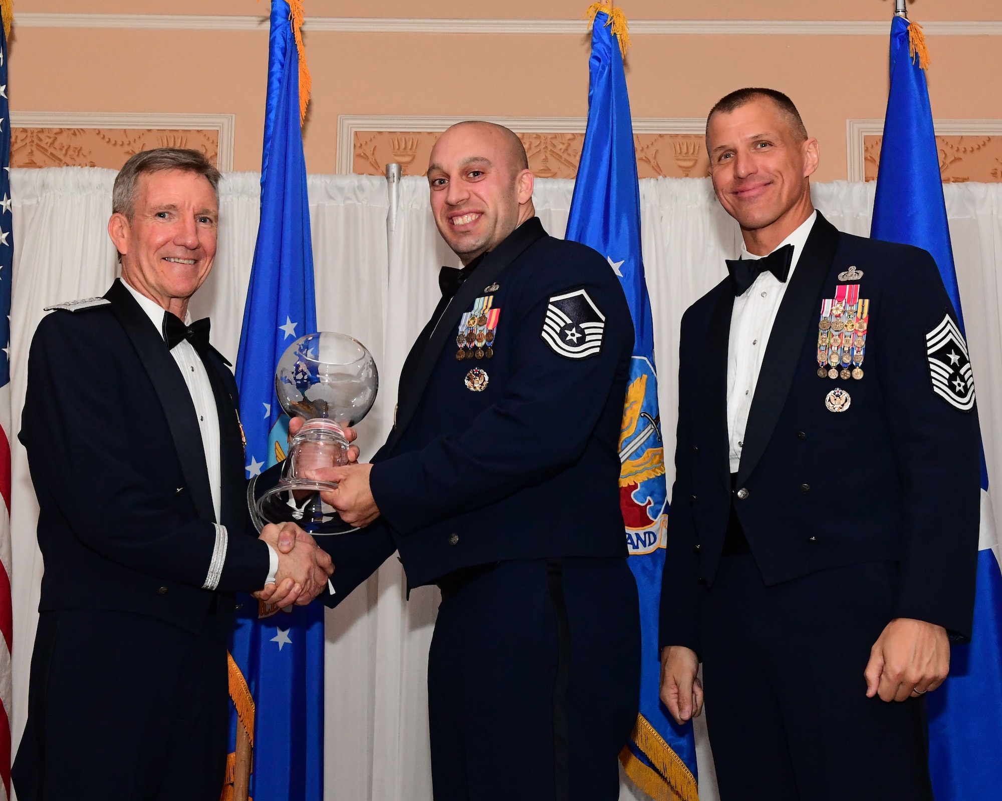 Gen. Hawk Carlisle, commander, Air Combat Command presents an award to Master Sgt. Josh Malyemezian, 55th Contracting Station assistant chief of the contingency support flight, Offutt Air Force Base, Nebraska, as Chief Master Sgt. Steve McDonald, command chief, ACC, observes during the 2017 Outstanding Airmen of the Year banquet at the Bayview Community Center at Langley AFB, Virginia, March 8, 2017. The award recognizes 12 outstanding enlisted service members for superior leadership, job performance, community involvement and personal achievements. (U.S. Air Force photo by Staff Sgt. Nick Wilson)