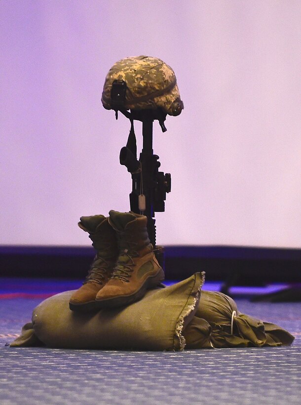 A an M-4 Carbine assault rifle with a helmet, boots and sandbags is displayed in honor of fallen service members, prisoners of war and those missing in action during the 2017 Outstanding Airmen of the Year banquet at the Bayview Community Center at Langley AFB, Virginia, March 8, 2017. Most official Air Force banquets and ceremonies have a moment of silent during events to pay tribute to more than 150, 000 Americans who are missing in action or have been held as prisoners of war. (U.S. Air Force photo by Senior Airman Kimberly Nagle)