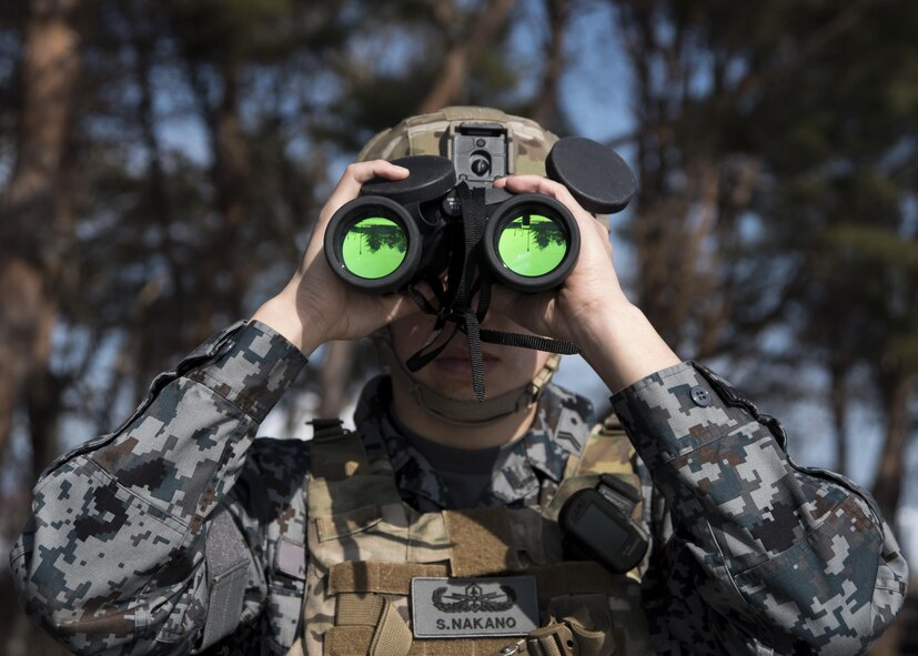 Japan Air Self-Defense Force Tech. Sgt. Shota Nakano, a Tohoku Explosive Ordnance Disposal school instructor, looks through binoculars down range while conducting initial training scenario reconnaissance at Misawa Air Base, Japan, March 2, 2017. Upon arriving at the location of an identified ordnance it is vital to confirm what type of ordnance it is in order to come up with an appropriate plan of approach, proper handling and safe disposal. (U.S. Air Force photo by Staff Sgt. Melanie A. Hutto)