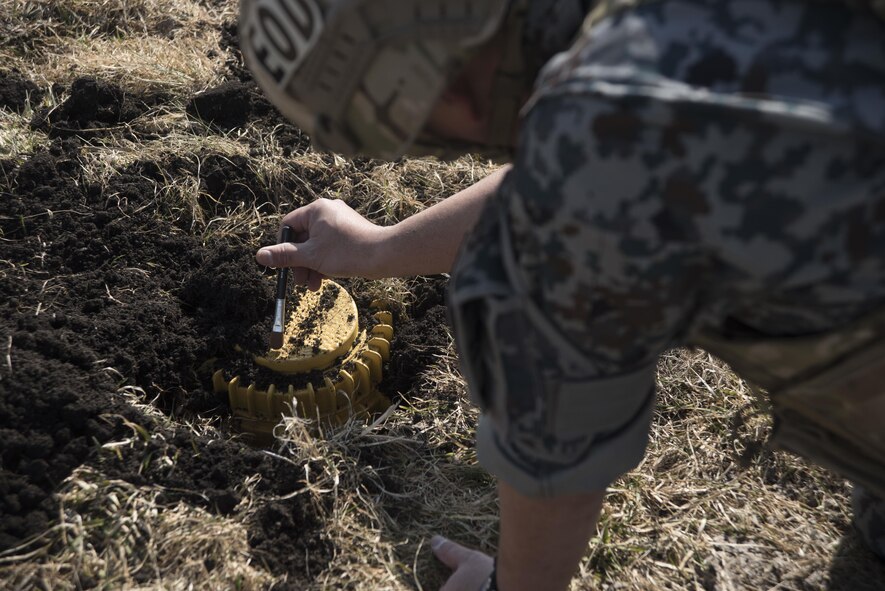 Japan Air Self-Defense Force Tech. Sgt. Shinji Okuzono, a Tohoku Explosive Ordnance Disposal school instructor, brushes dirt away from an unexploded ordnance during a close range reconnaissance training mission at Misawa Air Base, Japan, March 2, 2017. Closely examining an ordnance determines what procedures an EOD technician should use for safe removal. Over the course of two days the EOD team conducted four UXO-related operations: landmine and submunitions the first day, a cache and rocket and mortar the second day. (U.S. Air Force photo by Staff Sgt. Melanie A. Hutto)