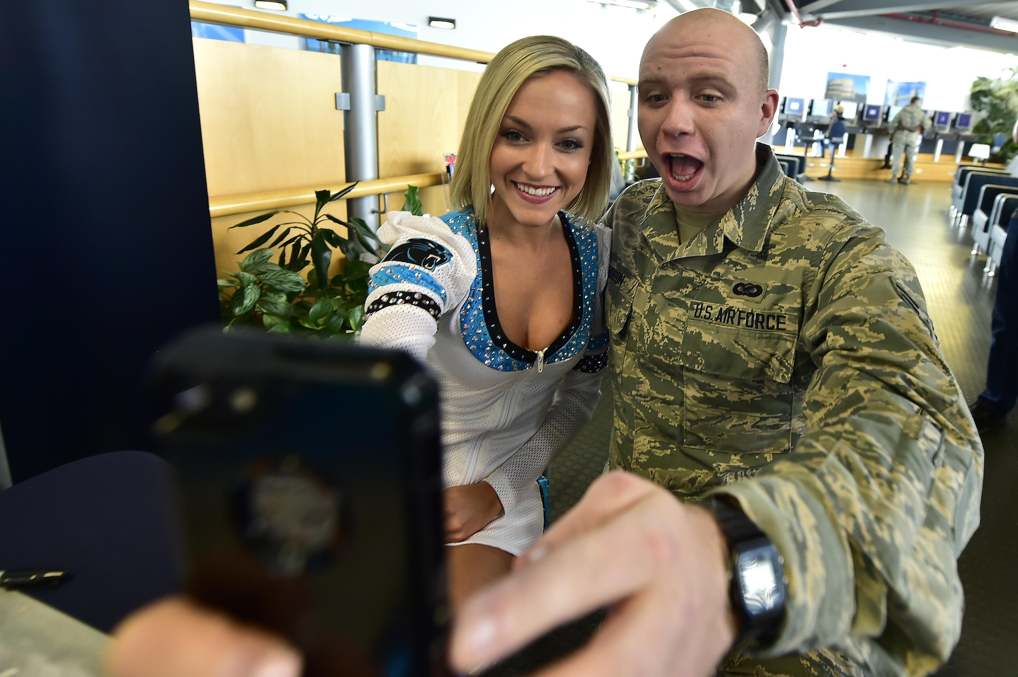 U.S. Air Force Airman 1st Class Sean Hudson, American Forces Network Sembach broadcast journalist, takes a selfie with Top Cats cheerleader Megan Schlosser during a meet and greet at the 721st Aerial Port Squadron’s Passenger Terminal on Ramstein Air Base, Germany, March 6, 2017. Five Panthers players and two cheerleaders traveled from Charlotte, North Carolina, to Germany as part of a United Services Organization tour. (U.S. Air Force photo by Senior Airman Jonathan Bass)