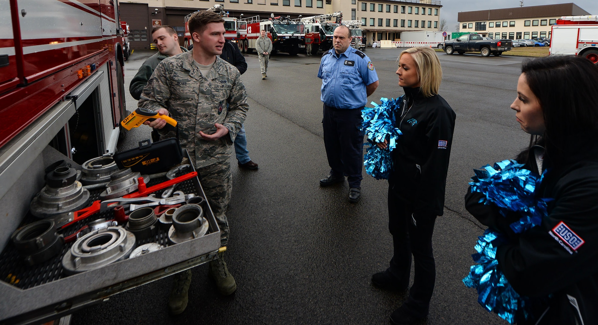 Senior Airman Stephen Bowe, 86th Civil Engineer Squadron firefighter, explains uses of the many tools on-board a fire engine to Carolina Panthers Top Cat cheerleaders Chandalae Lanouette and Megan Schlosser at Fire Station one on Ramstein Air Base, Germany, Mar. 7, 2017. While visiting Fire Station one the players and cheerleaders were allowed to view a simulated building fire response. (U.S. Air Force photo by Airman 1st Class D. Blake Browning)