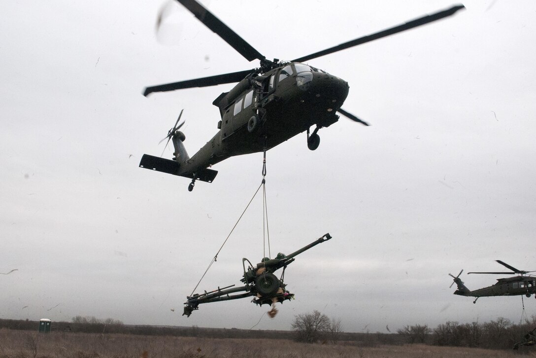 Two Oklahoma Army National Guard UH-60 Black Hawk helicopters take off with towed howitzers during slingload and live-fire training at Fort Sill, Okla., March 4, 2017. Oklahoma Army National Guard photo by Sgt. Bradley Cooney