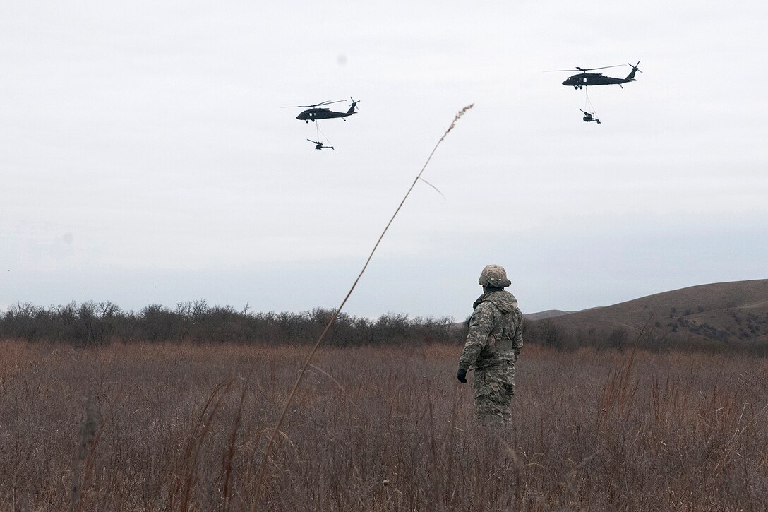 An Oklahoma Army National Guardsman watches as two UH-60 Black Hawk helicopters fly off during slingload and live-fire training at Fort Sill, Okla., March 4, 2017. Oklahoma Army National Guard photo by Sgt. Bradley Cooney