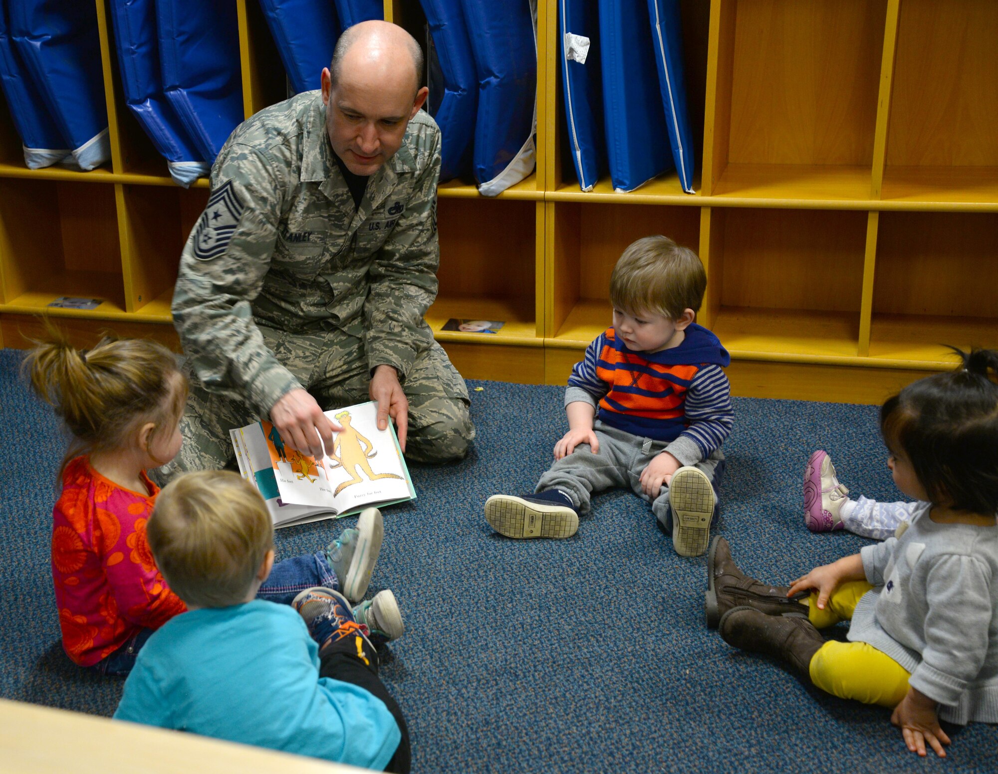 U.S. Air Force Chief Master Sgt. Curtis Stanley, 100th Air Refueling Wing command chief, center, reads a Dr. Seuss book to a circle of toddlers, March 3, 2017, at the Child Development Center on RAF Mildenhall, England. The CDC celebrated the author’s birthday by hosting Team Mildenhall commanders and promoting reading to their students. (U.S. Air Force photo by Senior Airman Justine Rho)
