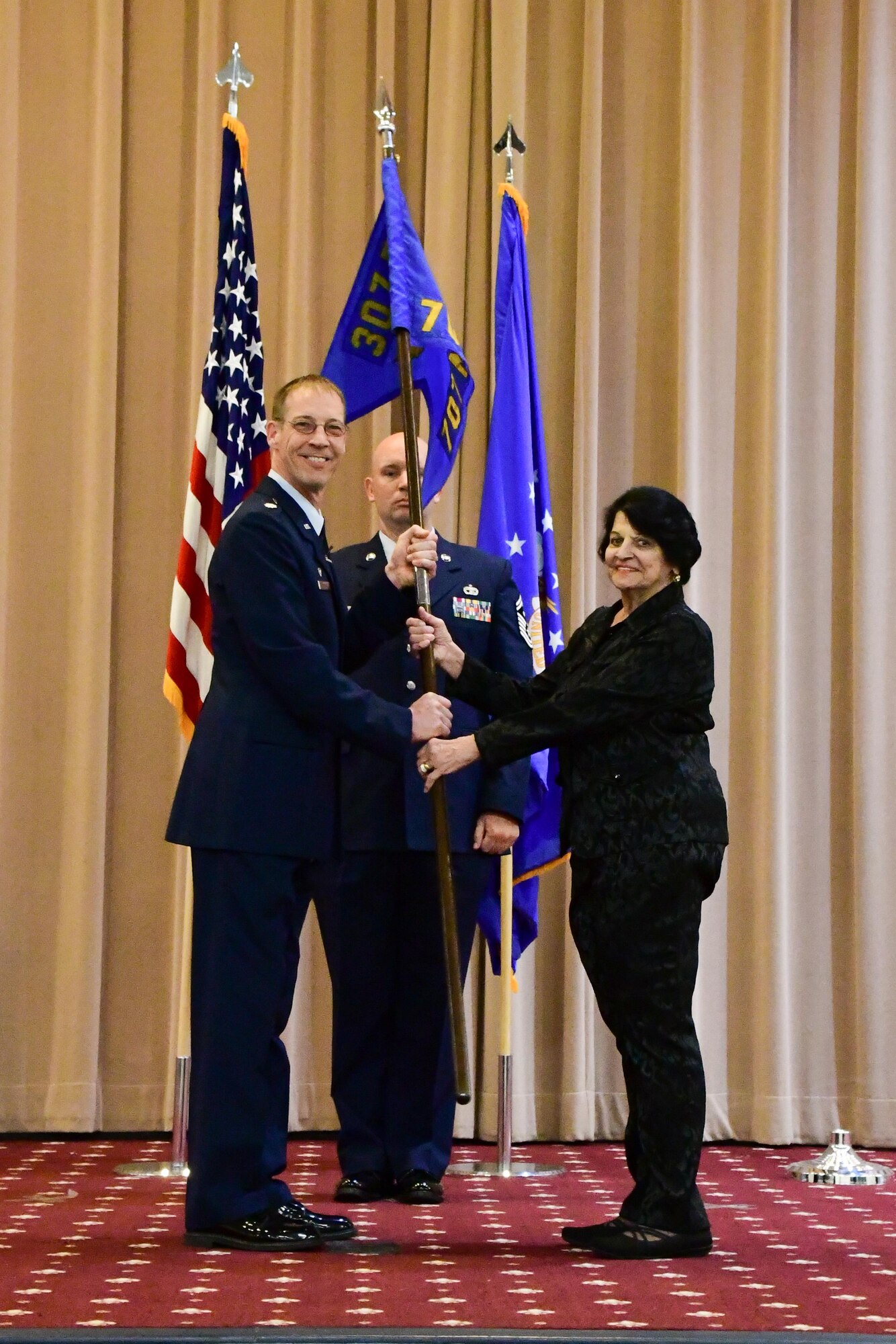 U.S. Air Force Lt. Col. Warren Crabtree, 707th Maintenance Squadron commander, presents the squadron guidon to Catherine Vanderberry, during an Honorary Commander Induction Ceremony at Barksdale Air Force Base, La. March 5, 2017. Vanderberry is the first honorary commander for the 707th Maintenance Squadron. (U.S. Air Force photo by Master Sgt. Dachelle L. Melville/Released)