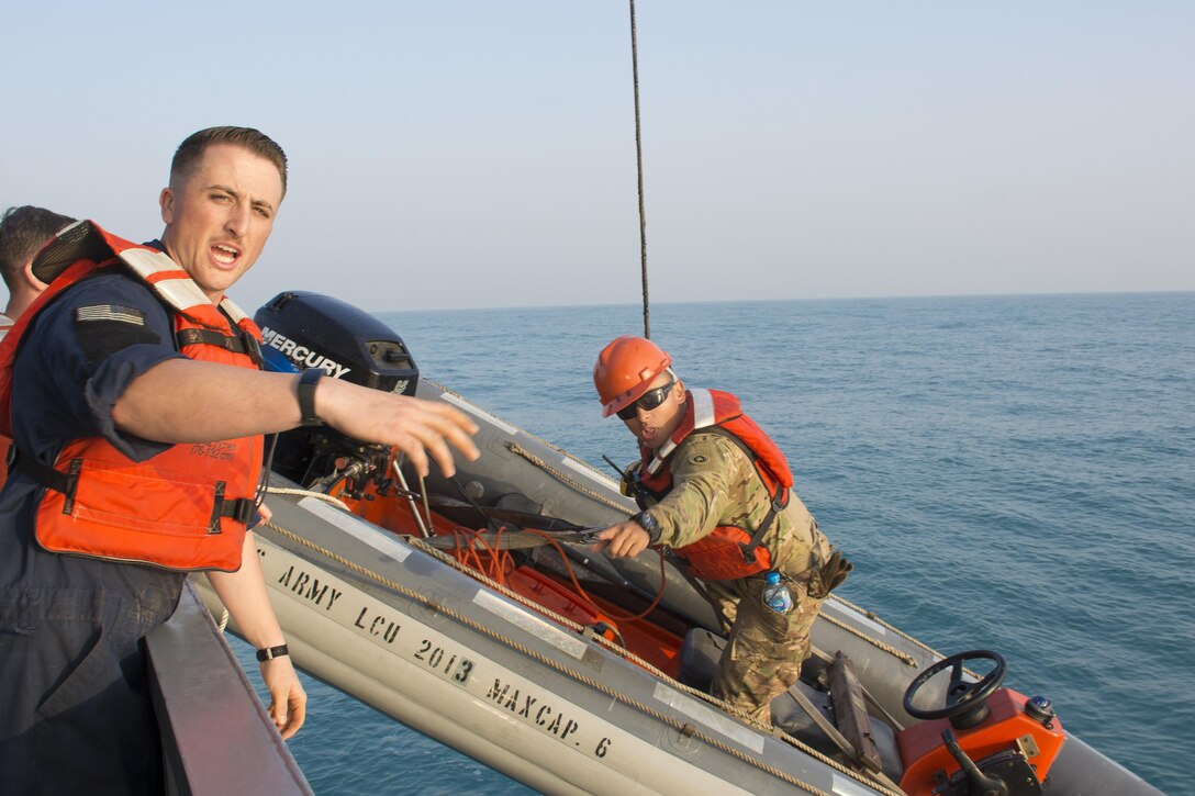 Kuwait- Army mariners from Detachment 1, 481st Transportation Company (Heavy Boat), California, aboard the LCU2013 Churubusco- a Landing Craft Utility vessel hoist a workboat back to the deck after running a personnel recovery training mission supporting the 77th Combat Aviation Brigade with an exercise replicating a downed aircraft scenario, Feb. 13. 
(Photo by Army Sgt. 1st Class Suzanne Ringle/Released)