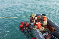 Kuwait-The Soldiers, Watercraft Operators and vessel medic, for the LCU2013 Churubusco- a Landing Craft Utility vessel from Detachment 1, 481st Transportation Company, California, grab a line thrown from the deck to hoist their mock patient from 77th Combat Aviation Brigade, Arkansas, while participating in a personnel recovery mission replicating a downed aircraft scenario, Feb. 13. 
(Photo by Army Sgt. 1st Class Suzanne Ringle/Released)