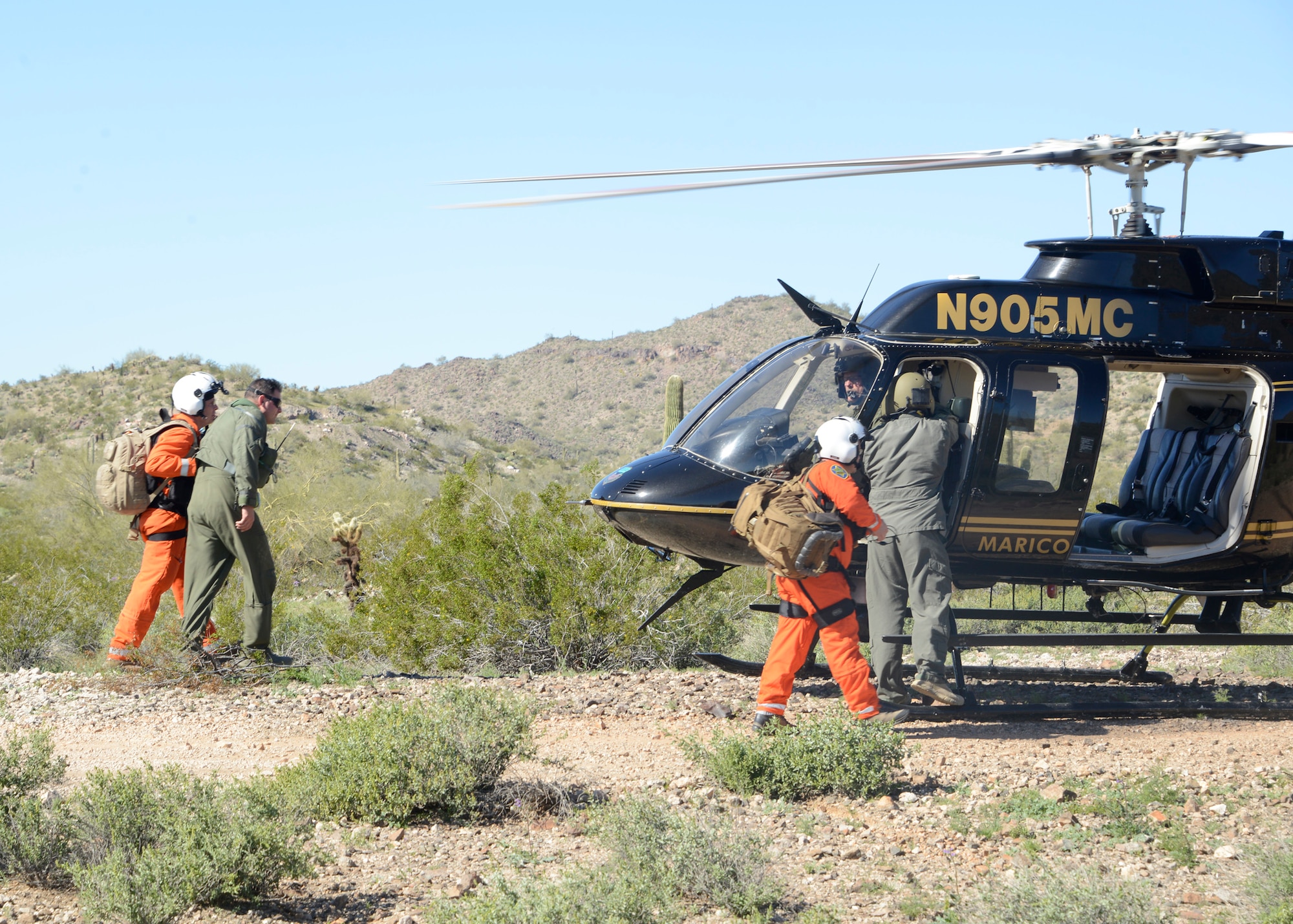 Mariacopa County Search and Rescue team guides Maj. Nicholas Suppa, 56th Operations Support Squadron  assistant director of operations, to the helicopter during a Major Accident Response Exercise at a remote area in Arizona, 1 Mar. 2017. The exercise highlighted the real way Air Force and civilian assets can be used together to more effectively respond to crises, and potentially save lives. (U.S. Air Force photo by Senior Airman Devante Williams)