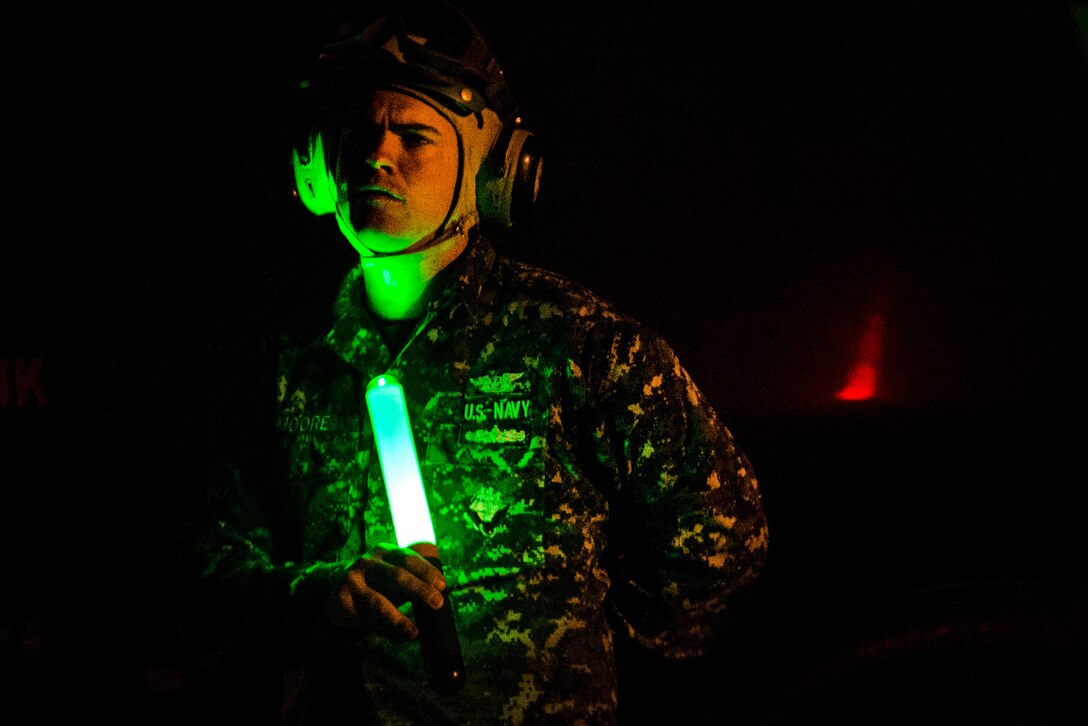 A sailor uses a flashlight to guide an MH-60S Seahawk helicopter on the flight line during Emerald Warrior 17 at Hurlburt Field, Fla., March 2, 2017. Air Force photo by Staff Sgt. Corey Hook 