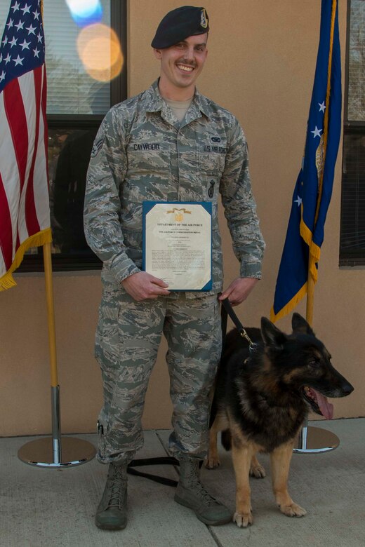 Senior Airman Brandon Caywood, 11th Security Support Squadron military working dog handler, and Teo, 11th SSPTS MWD, pose for a photo during Teo’s retirement ceremony at Joint Base Andrews, Md., March 9, 2017. Caywood held the certificate for Teo’s Air Force Commendation Medal that was awarded to him after serving 10 years as an Air Force explosive detection dog. (U.S. Air Force photo by Airman 1st Class Valentina Lopez)